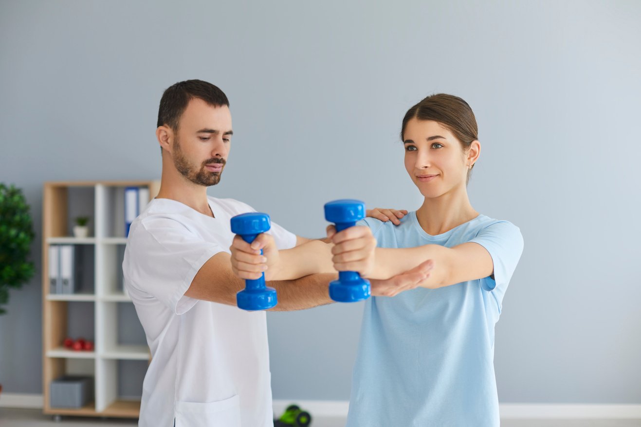 Chiropractor or Osteopath Fixing Woman Patient with Dumbbels in Right Position for Pain Relief